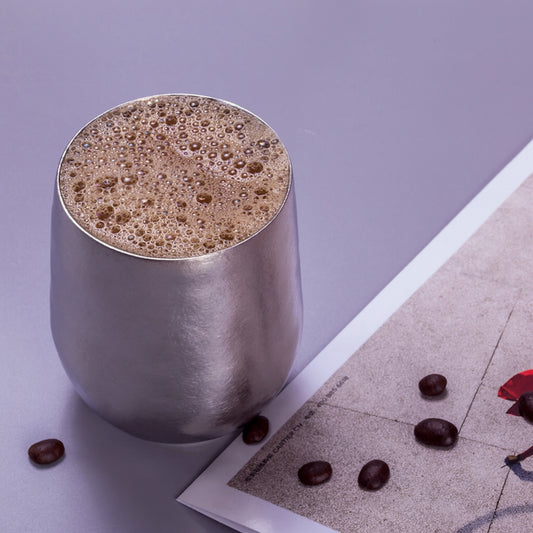 Egg-shaped titanium cup top view with coffee foam